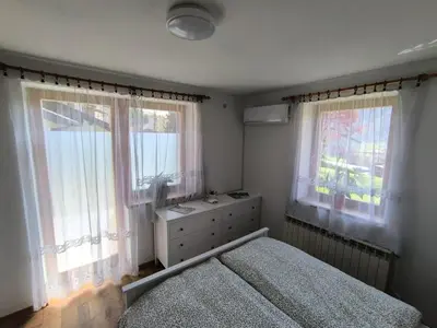 a bedroom with a bed and two windows at Apartma Pri noni Silvi in Tolmin