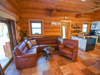 a living room with brown leather couches and a kitchen at Luxury Log House in Globoko