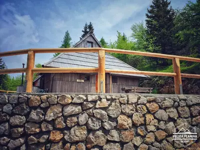 a stone wall in front of a wooden building at Chalet Pehta Velika Planina in Stahovica