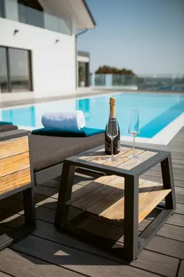a bottle of wine and a glass on a table next to a pool at Carolina Luxury Stay in Rogašovci