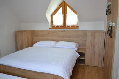 a bed with a wooden headboard and a window at Apartments Prekmurska vas - Vital Resort in Moravske Toplice
