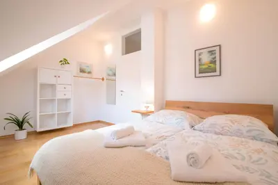 a white bedroom with a bed with towels on it at Trubarjeva 12 - The view in Ljubljana