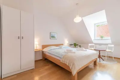 a white bedroom with a bed and a table at Trubarjeva 12 - The view in Ljubljana