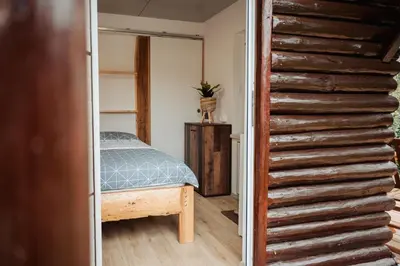 a bedroom with a bed and a wooden staircase at Koča ob ribniku in Ponikva