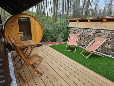 two chairs sitting on a wooden deck with a building at Koča ob ribniku in Ponikva