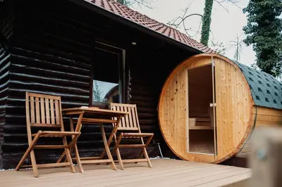 two chairs and a table outside of a log cabin at Koča ob ribniku in Ponikva