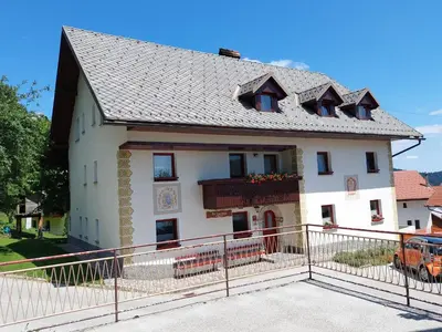 a white house with a balcony and a fence at Apartma Pri Tavčarju in Poljane nad Škofjo Loko