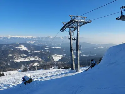 a snow covered slope with a ski lift in the background at Apartma Pri Tavčarju in Poljane nad Škofjo Loko