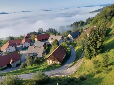 a village in the hills with fog in the distance at Apartma Pri Tavčarju in Poljane nad Škofjo Loko