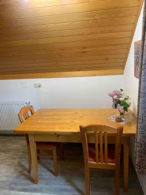 a wooden table with two chairs and a wooden ceiling at Apartma Pri Tavčarju in Poljane nad Škofjo Loko