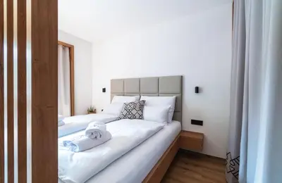 a bedroom with two beds with white sheets and towels at Gora Luxury Apartments in Kranjska Gora
