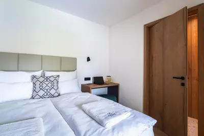 a bedroom with a white bed and a wooden door at Gora Luxury Apartments in Kranjska Gora