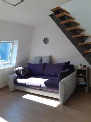 a couch in a living room under a staircase at Apartma Misha in Bovec