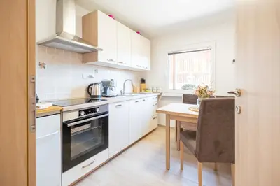 a kitchen with white cabinets and a wooden table at Apartment By The Forest in Zgornje Gorje