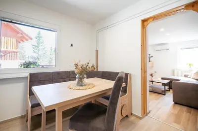 a dining room with a table and a couch at Apartment By The Forest in Zgornje Gorje