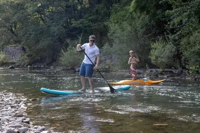 a man is standing on a paddle board in the water at apartma Aljaž in Spodnja Idrija