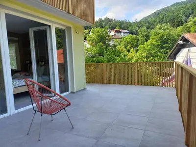 a red chair sitting on a patio with a balcony at apartma Aljaž in Spodnja Idrija