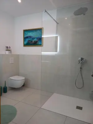 a white bathroom with a shower and a toilet at apartma Aljaž in Spodnja Idrija