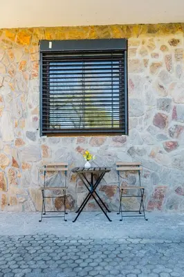a table and two chairs in front of a stone wall at Apartma Tom in Metlika