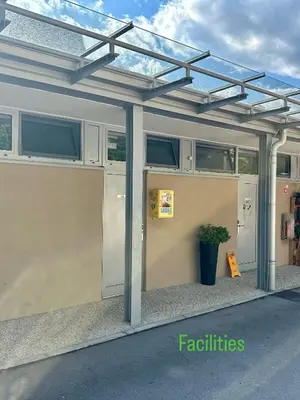 a building with a garage with awning and a potted plant at Kamp Tura- camping pitch only in Vipava