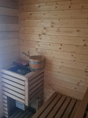 a sauna with a wooden wall and a wooden bench at Mobile Home Cabana with HotTub&Sauna in Spodnja Polskava