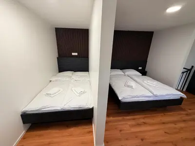two beds in a room with white walls and wood floors at Resort PJagodic in Cerklje na Gorenjskem