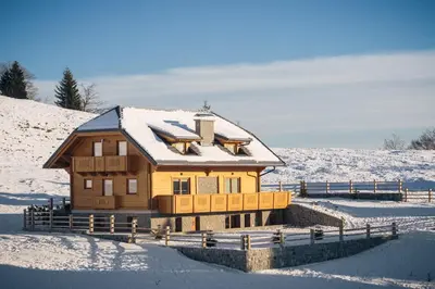 a wooden house with snow on the roof at Apartments Krvavec in Cerklje na Gorenjskem