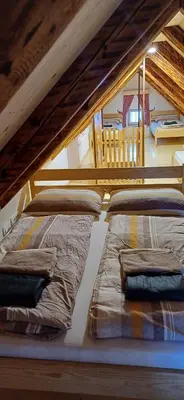 two beds in a room with a loft at HIŠA Margit in Rateče