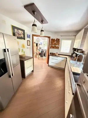 a kitchen with white appliances and a wooden floor at Vila Tin & Koča Tin in Prestranek