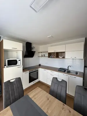 a kitchen with white cabinets and a table and chairs at Apartma Moravske Toplice 6 in Moravske Toplice