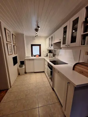 a kitchen with white cabinets and a tile floor at Katja Cottage in Bohinjska Bela