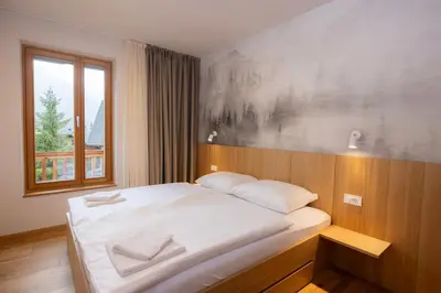 a bedroom with a large white bed with a window at Apartments Alpine Nest in Kranjska Gora