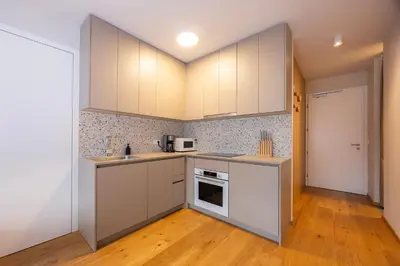 a kitchen with white cabinets and a wooden floor at Apartments Alpine Nest in Kranjska Gora