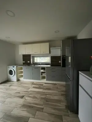 a large kitchen with white cabinets and a refrigerator at Apartment Mina in Radovljica
