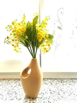 a vase with yellow flowers in it sitting on a counter at Topel dom v središču mesta 2 in Maribor