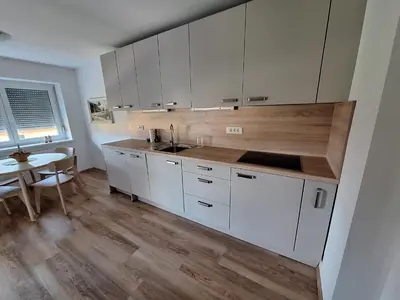 a kitchen with white cabinets and a wooden floor at SummerHouse in Jesenice