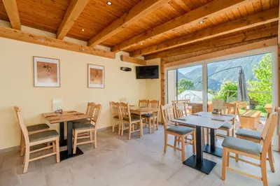 a dining room with tables and chairs and a large window at Penzion Hosnar in Bovec