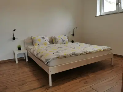 a bed in a white room with a bedskirtspectspectspectspects at Apartma Lipa in Veliki Gaber