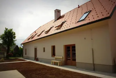 a white building with a red roof and a bench at Smrekarjeva Domačija in Postojna