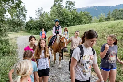 a girl riding a horse with a group of kids at Smrekarjeva Domačija in Postojna
