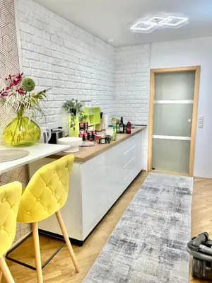 a kitchen with white cabinets and a brick wall at Topel dom v središču mesta in Maribor