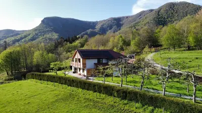 a house in a field with mountains in the background at Hiša na Hribu- A Peaceful Hilltop Escape above river Kolpa in Kostel