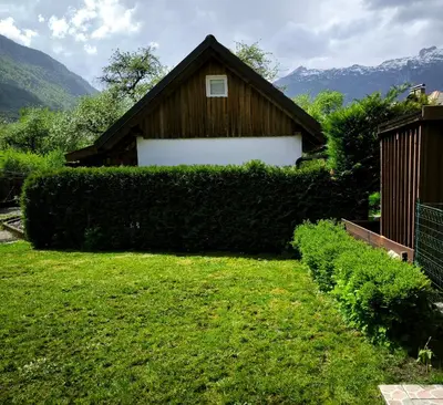a house with a hedge in front of a building at Garden Apartment Pejić - near Bovec, Soča Valley in Bovec