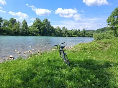 a bike parked in the grass next to a river at LAND FOR YOUR TENT NEXT TO A RIVER price includes lands in Croatia and Bosnia as well USE THE PINPOINT LOCATION AND NOT MY HOME ADDRESS BEBLERJEV TRG TO GET TO YOUR ACCOMMODATION bathroom is a bit different so check YouTube video DuskoThreeCountries in Ljubljana