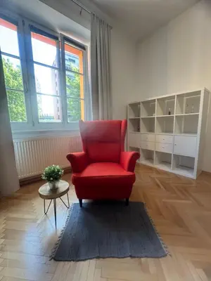 a living room with a red chair and a table at Feel good Stay at Dragon bridge Apartment in Ljubljana