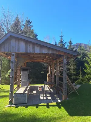 a wooden pavilion with a bench in the grass at Na Rebri in Luče