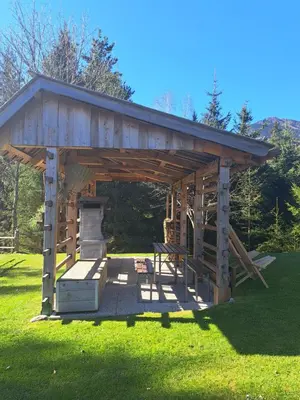 a wooden gazebo with a stove in the grass at Na Rebri in Luče