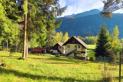 a house in a field with mountains in the background at Chalet Gorske Sanje - Kranjska Gora in Gozd Martuljek