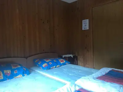 two twin beds in a room with wooden walls at Planinski dom - Mihov dom na Vršiču in Kranjska Gora