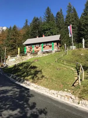 a building on a hill next to a road at Planinski dom - Mihov dom na Vršiču in Kranjska Gora